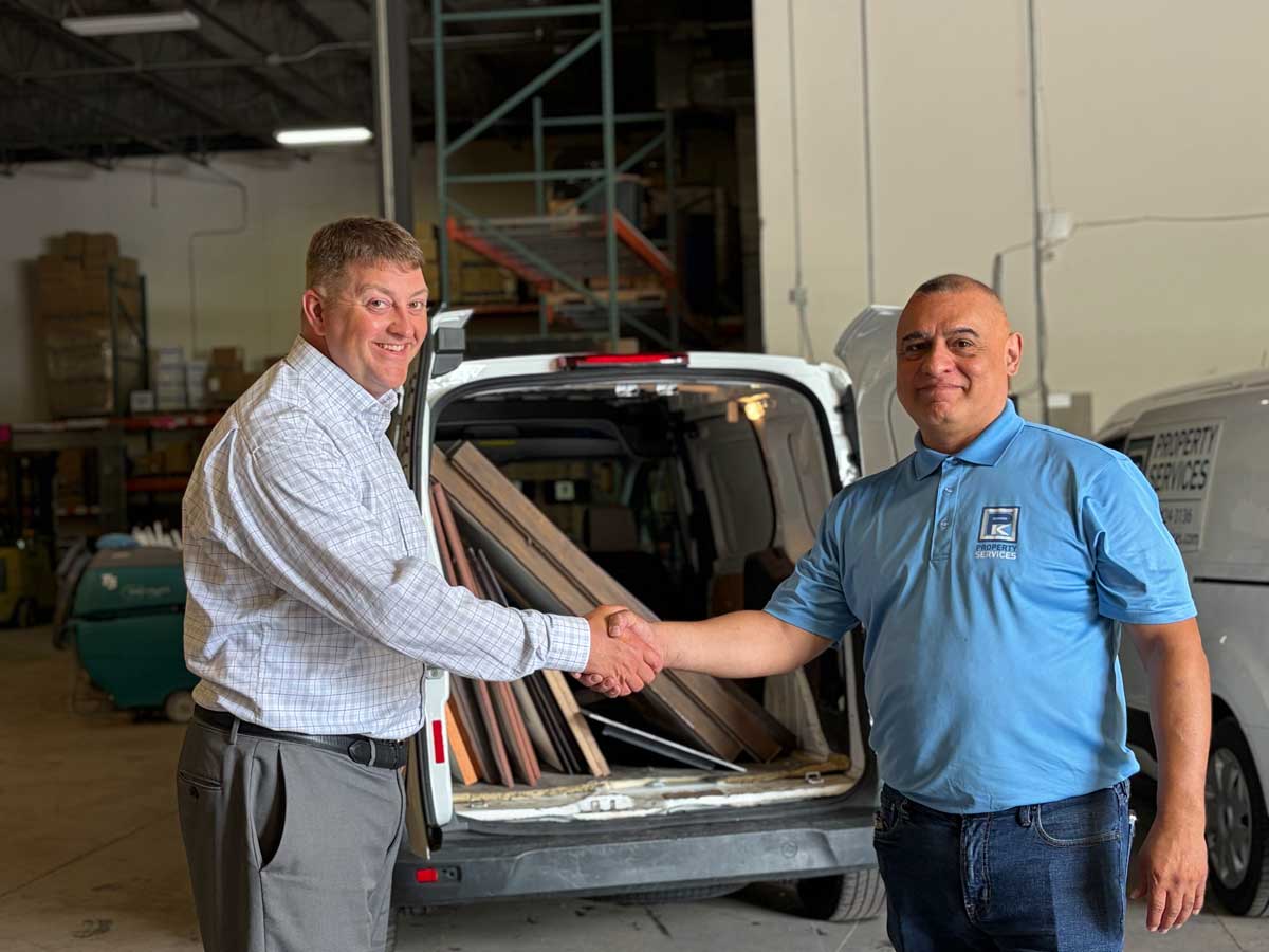 Two men shaking hands beside loaded service van