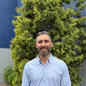 Smiling bearded man in blue shirt outdoors
