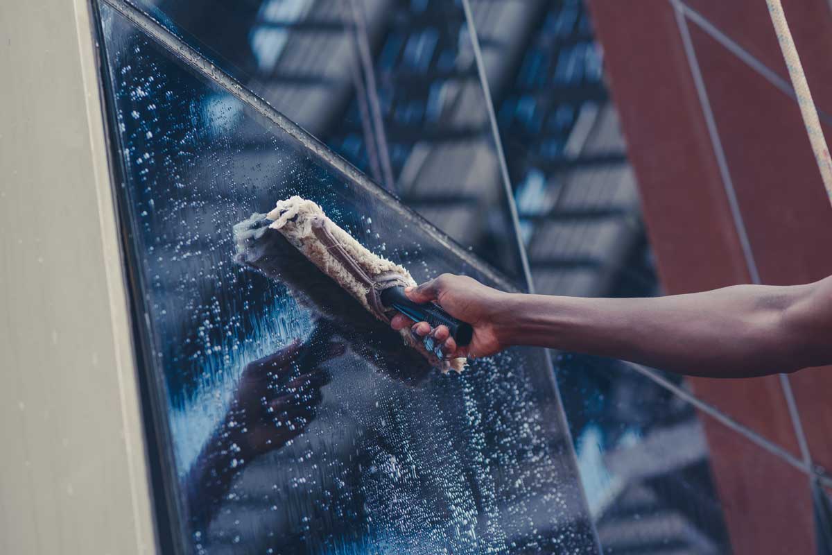 Photo of a person washing commercial windows with a squeegee.