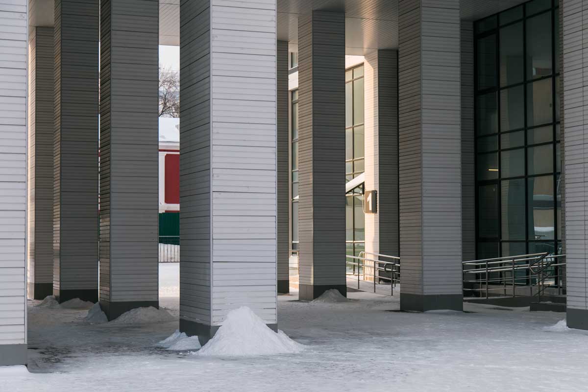 Snow-covered modern building entrance with tall columns